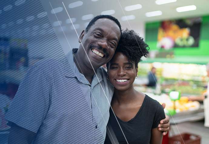 Man with his arm around a young woman at the grocery store smiling