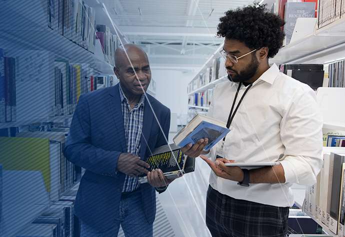 Two men looking at a book in a library together